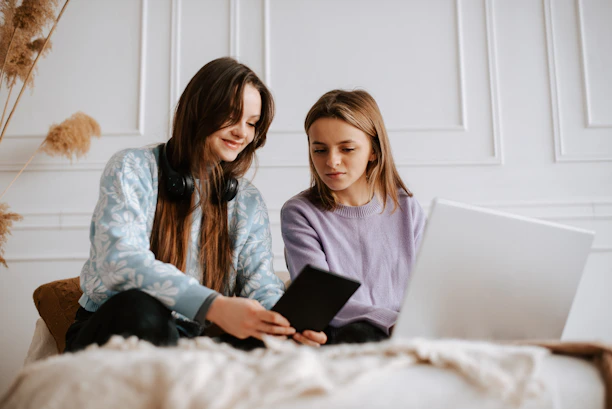 Two friends happily sharing a tablet screen, enjoying streaming content together.