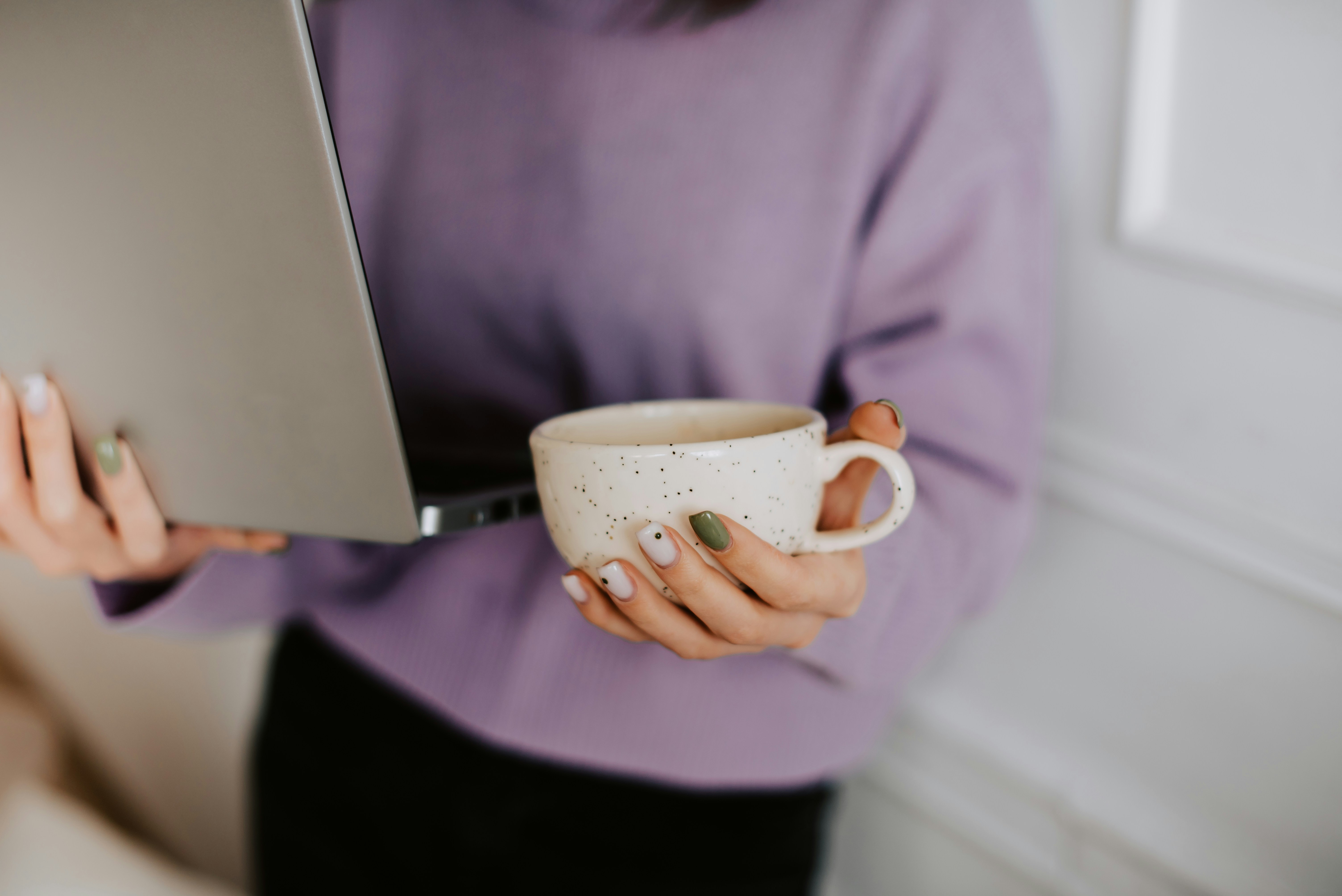a woman holding a coffee cup and a laptop