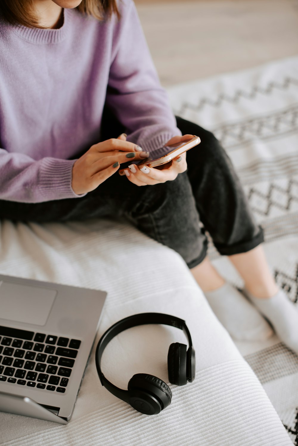 a woman sitting on a bed looking at her cell phone