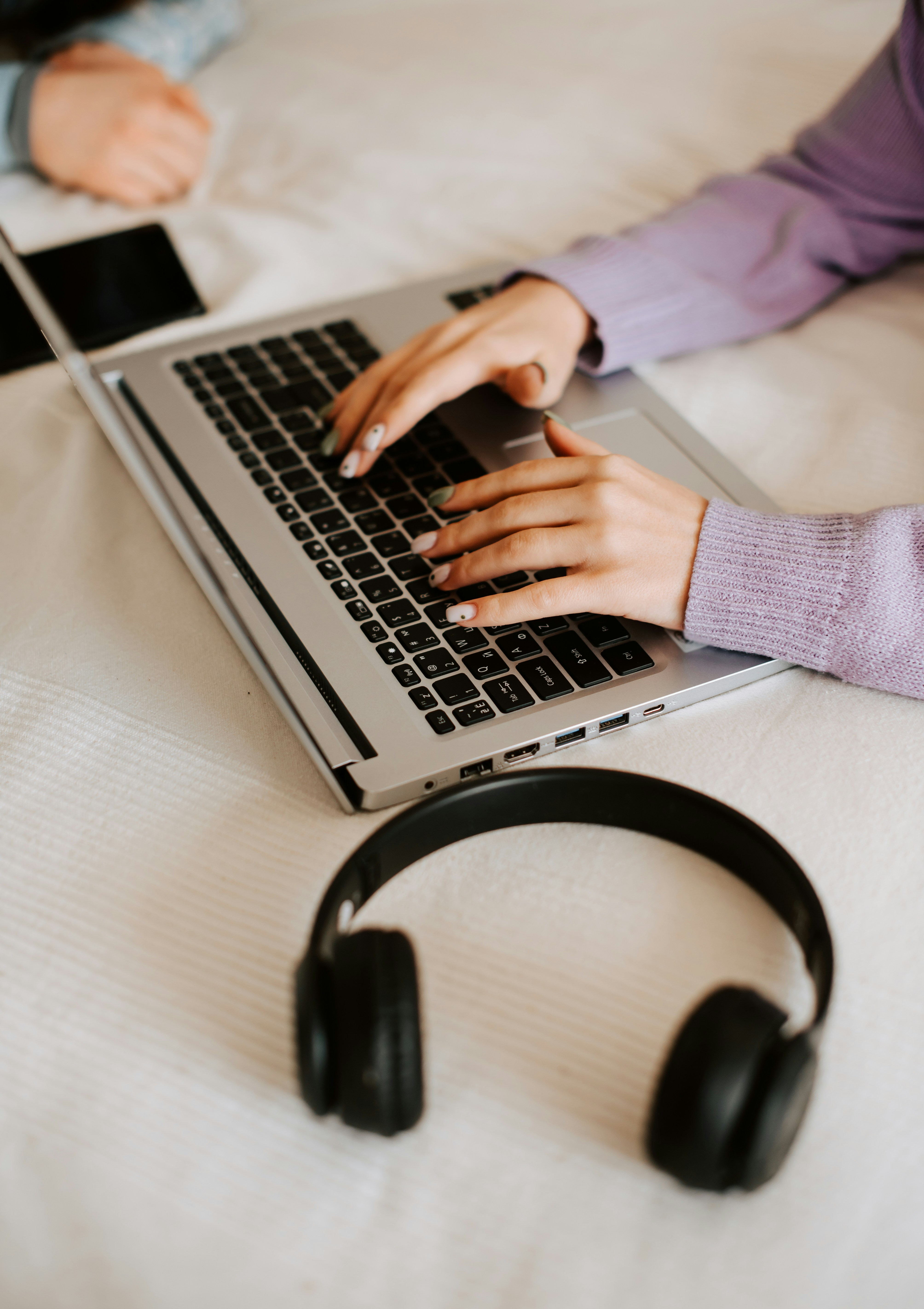 a person typing on a laptop on a bed
