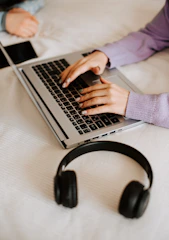 a person typing on a laptop on a bed