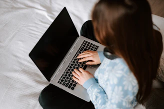 a woman sitting on a bed using a laptop computer