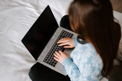 a woman sitting on a bed using a laptop computer