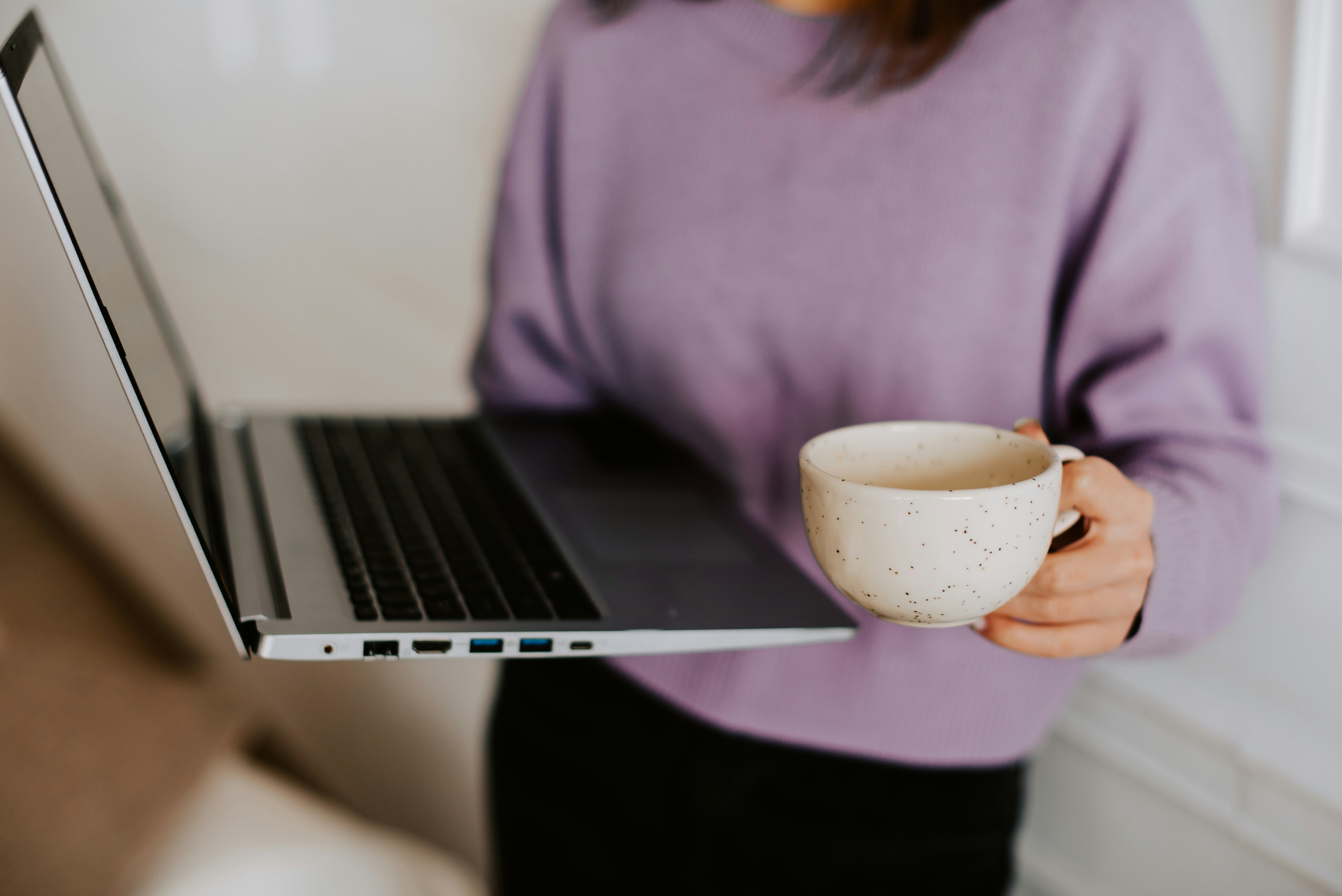 a woman holding a coffee cup and a laptop