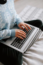 a woman sitting on a bed using a laptop computer