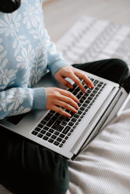 a woman sitting on a bed using a laptop computer