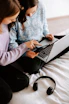 two girls sitting on a bed using a laptop
