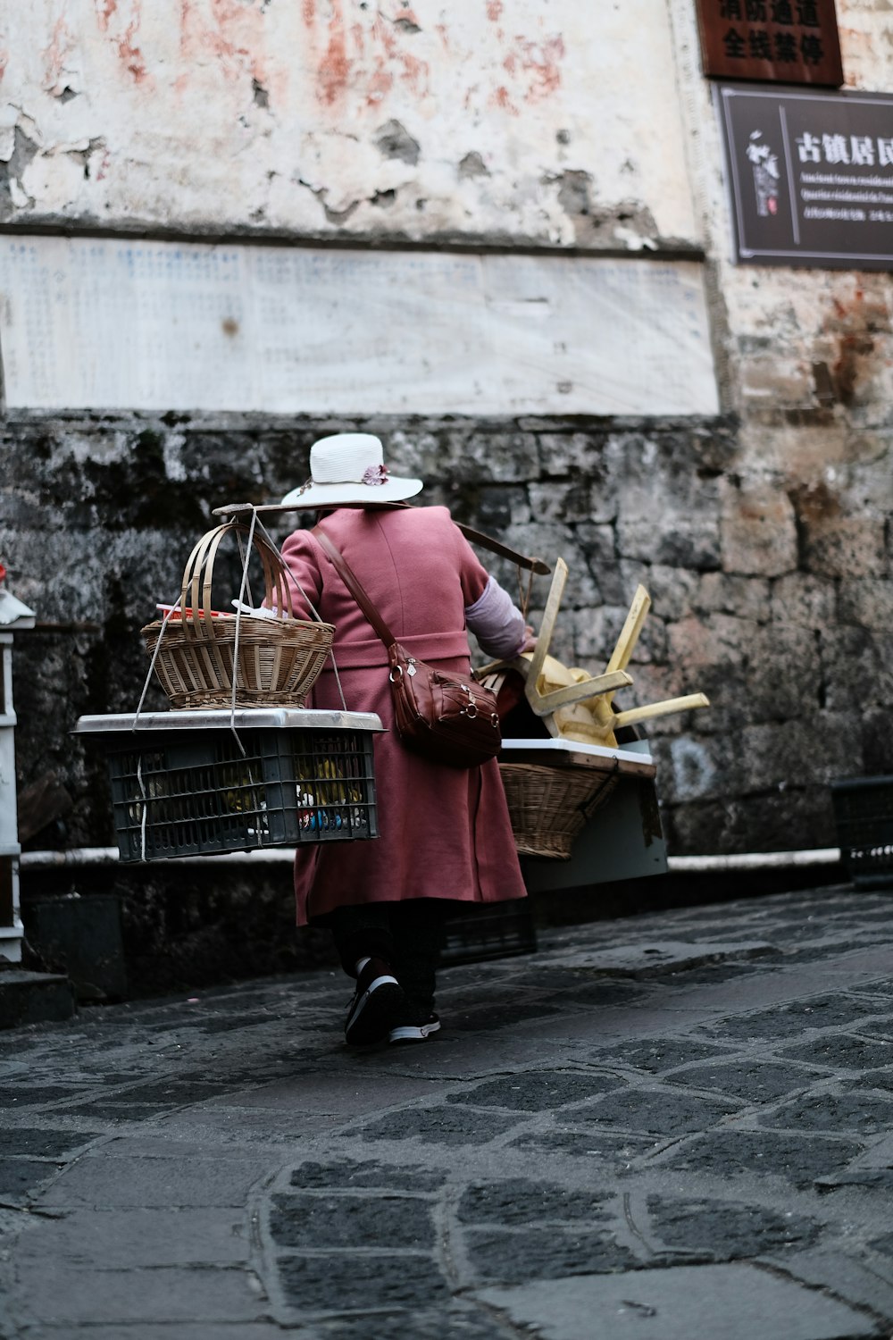 a woman walking down a street carrying a basket