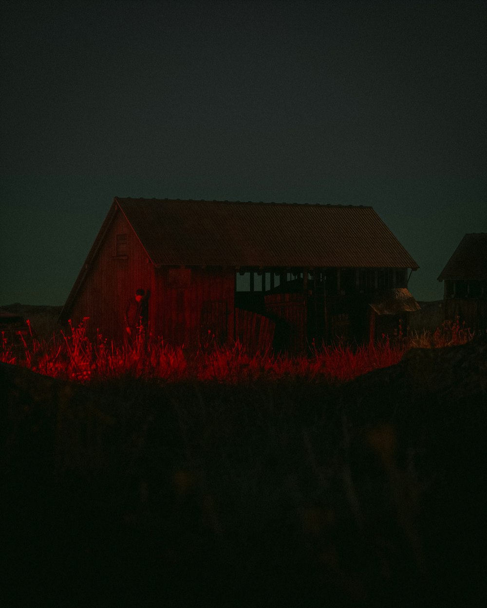 a barn in the middle of a field at night