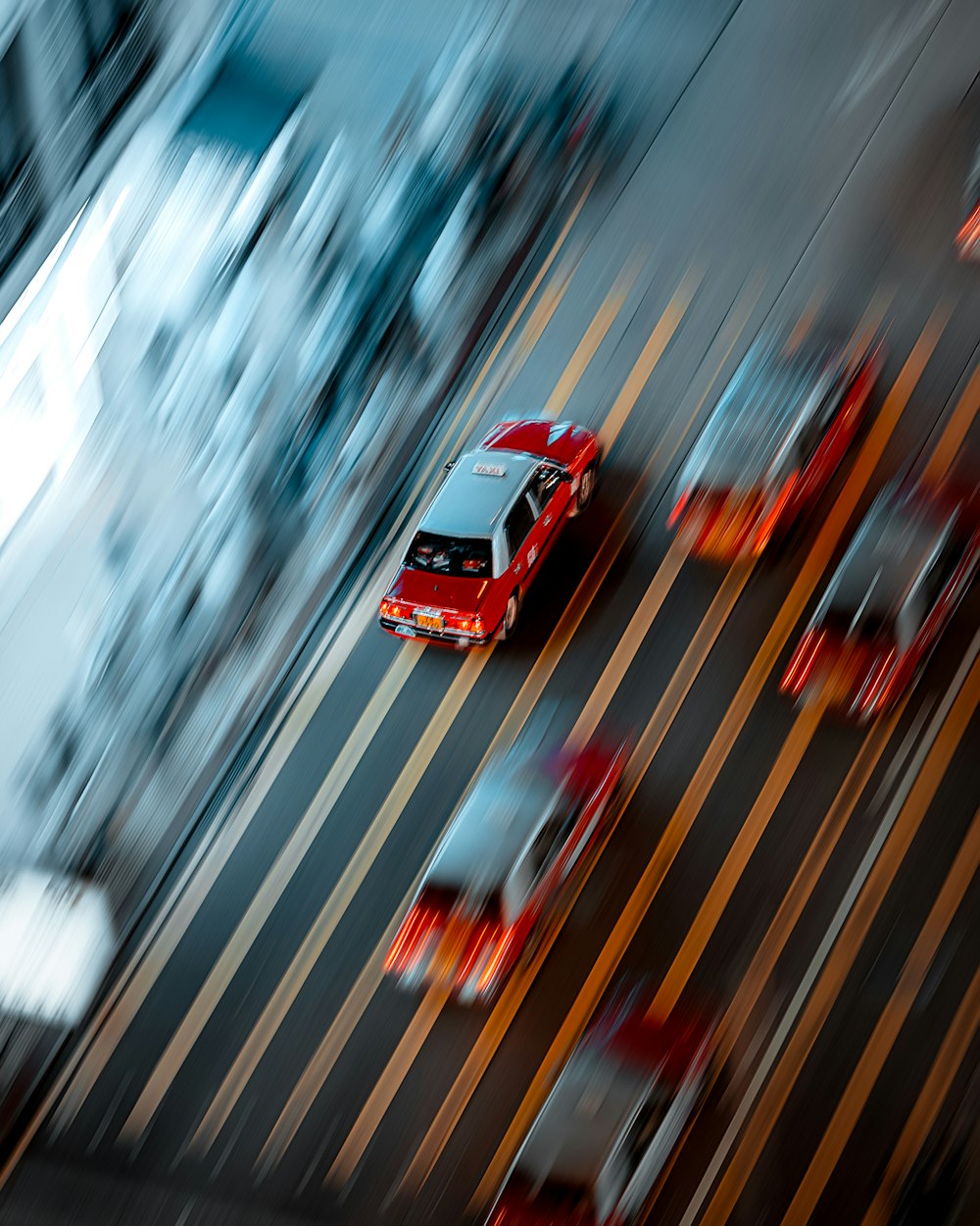 a red car driving down a street next to tall buildings