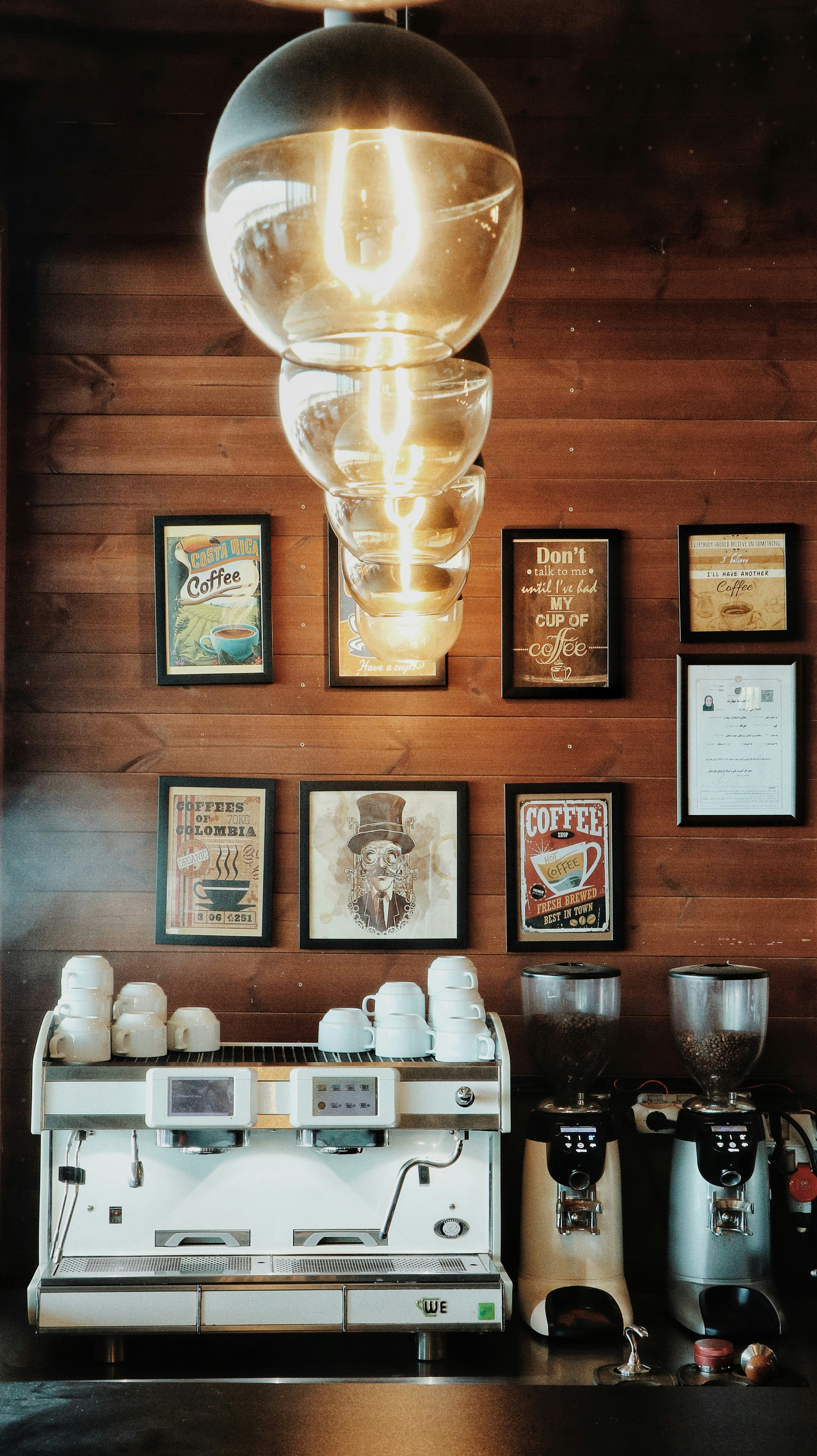 uma máquina de café sentada ao lado de uma parede com fotos sobre ela