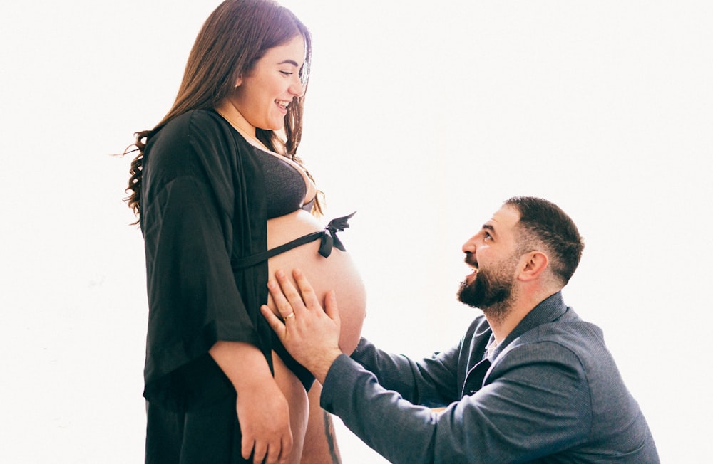 a pregnant man holding his pregnant wife's belly