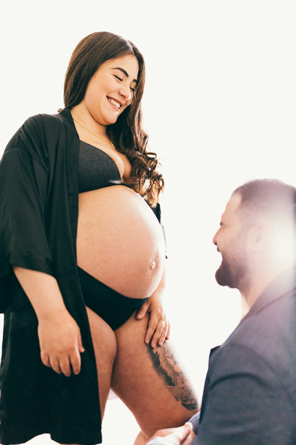 a pregnant woman in a black dress is standing next to a man