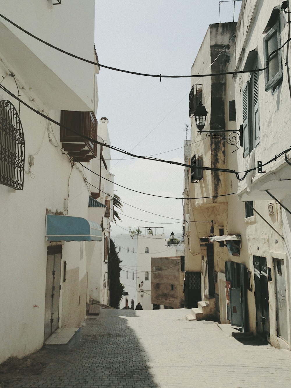 a narrow street with buildings and a blue awning