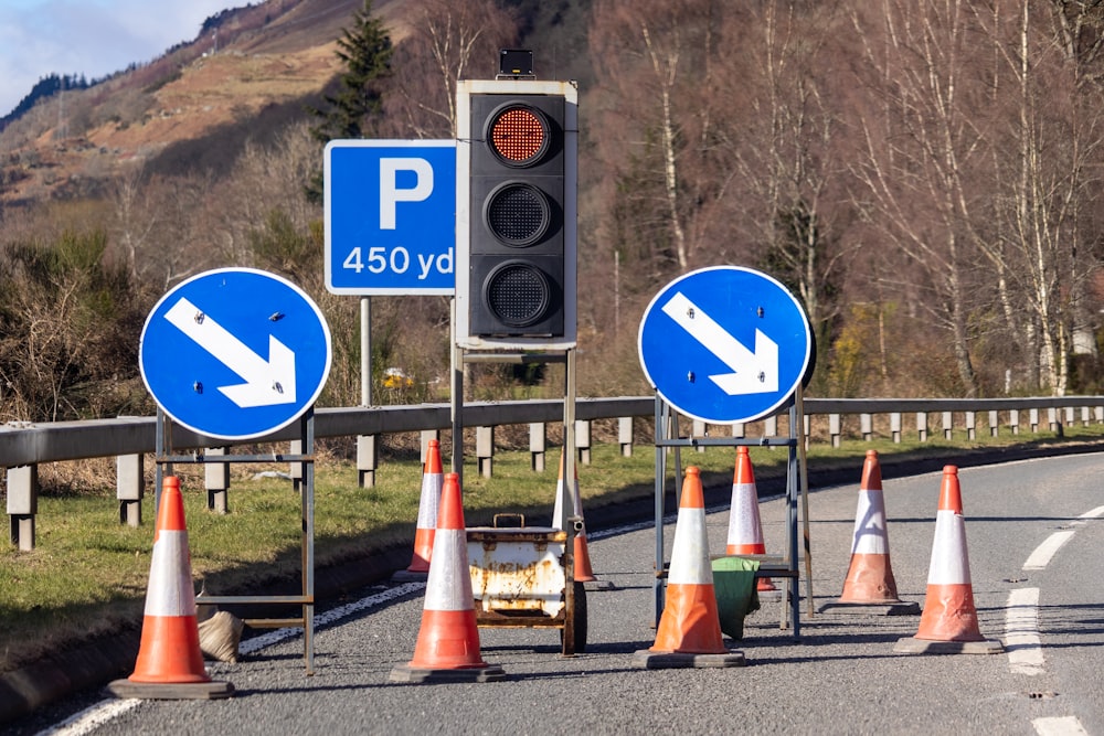 traffic cones and signs on a road with a mountain in the background