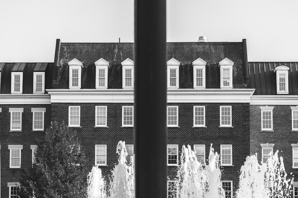 a black and white photo of a fountain in front of a building