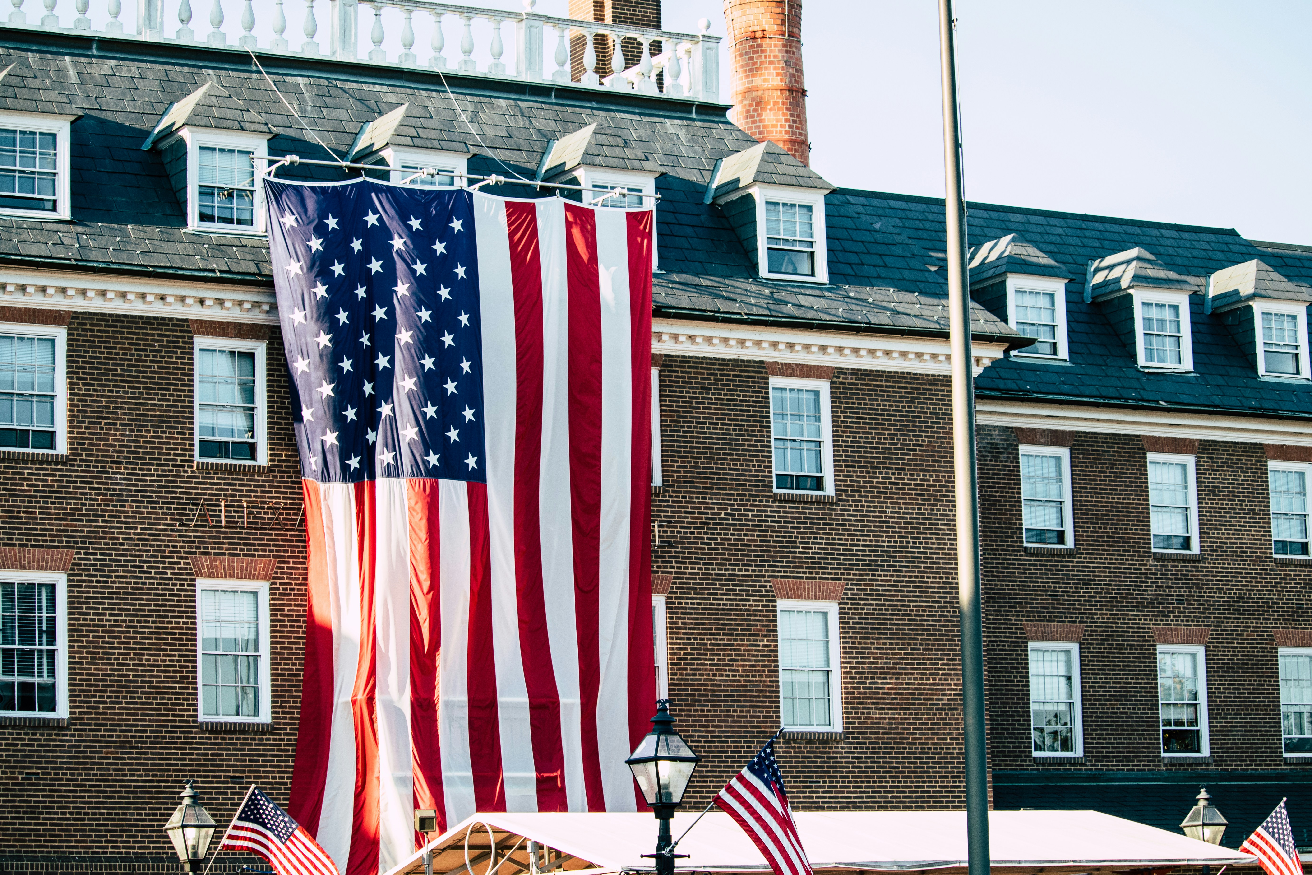 a large american flag hanging from the side of a building