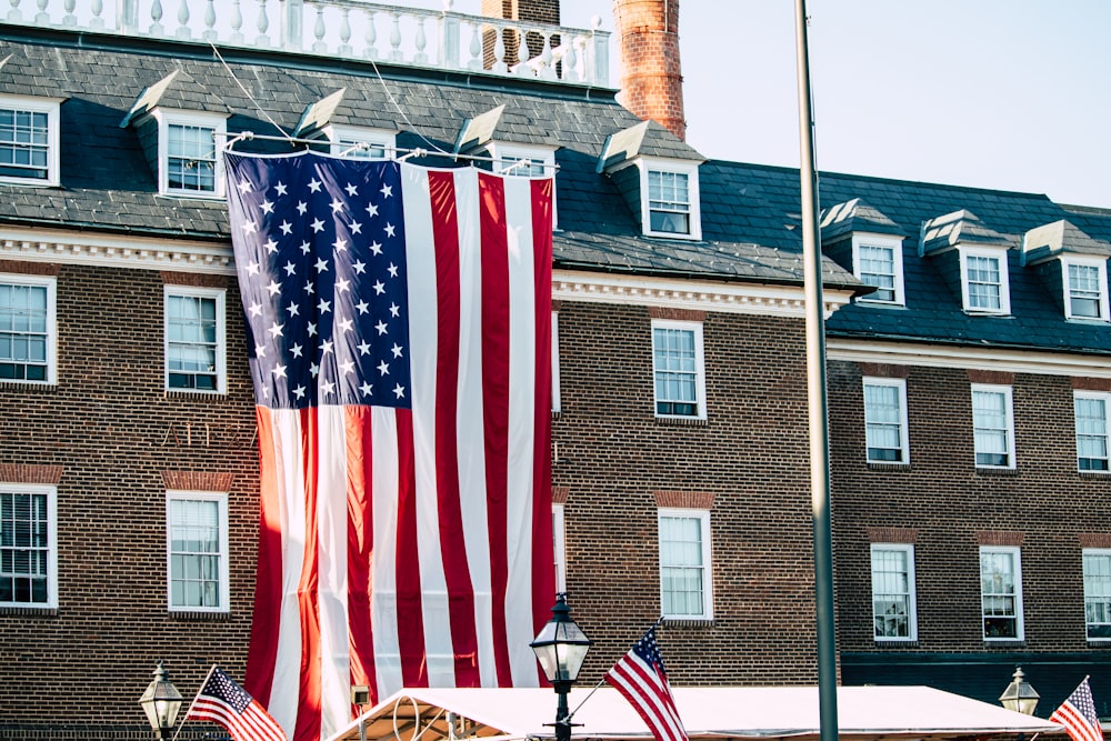 a large american flag hanging from the side of a building