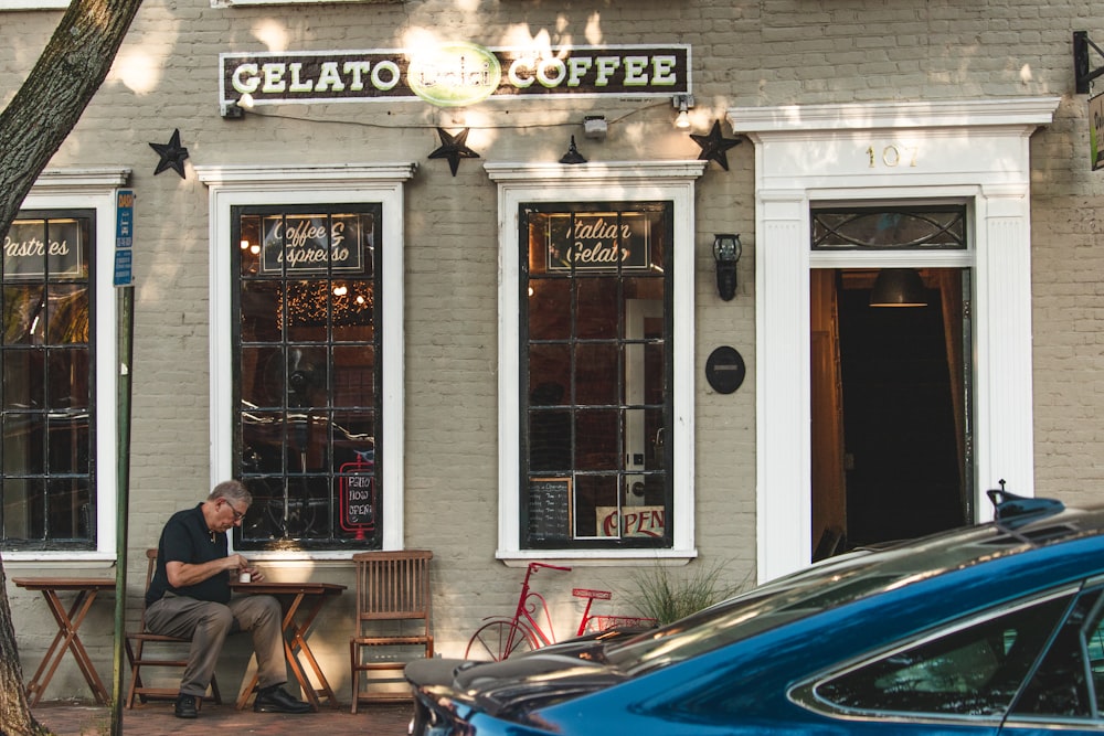 a man sitting at a table outside of a coffee shop