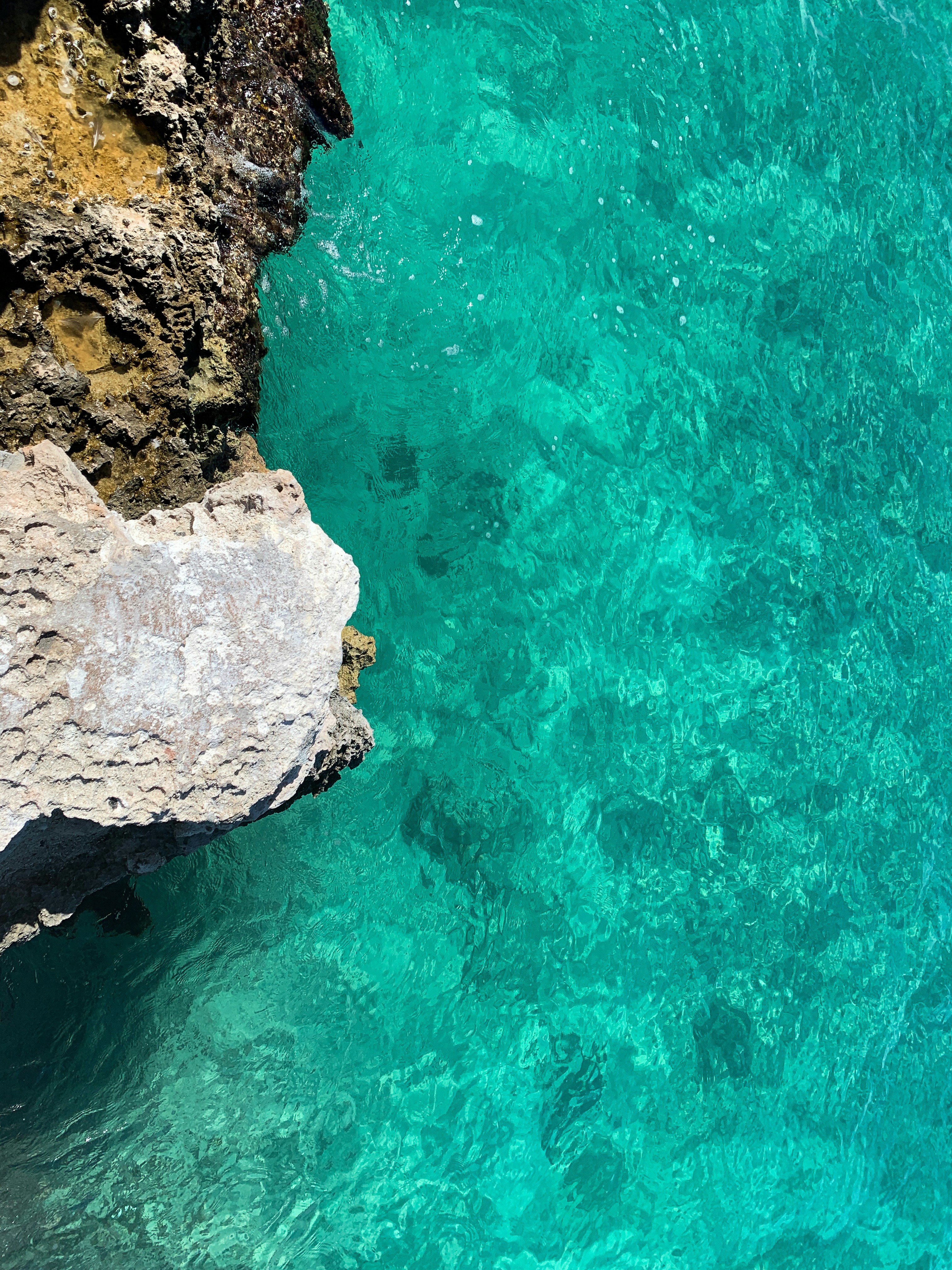 Светлый прибрежный утёс и каменистая кромка моря.