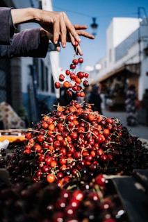 a pile of cherries being picked from a bin