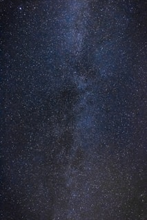 An expansive view of a star-filled night sky with countless stars spread across a dark, vast background. The dense cluster of stars suggests the presence of a galaxy, possibly the Milky Way, adding depth and complexity to the scene.