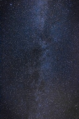 An expansive view of a star-filled night sky with countless stars spread across a dark, vast background. The dense cluster of stars suggests the presence of a galaxy, possibly the Milky Way, adding depth and complexity to the scene.