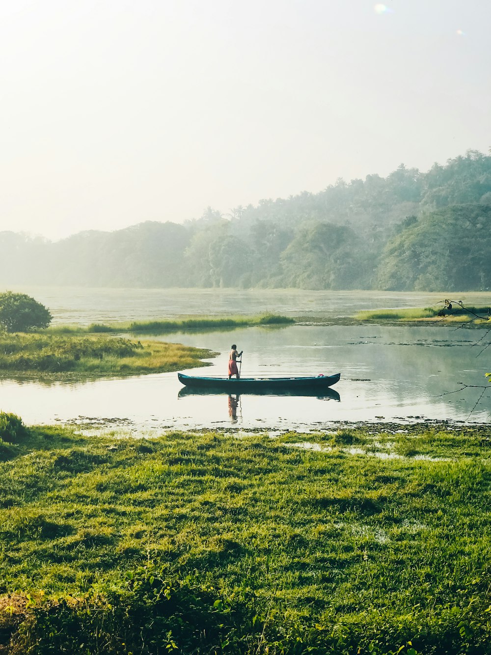 a man standing in a boat on top of a lake