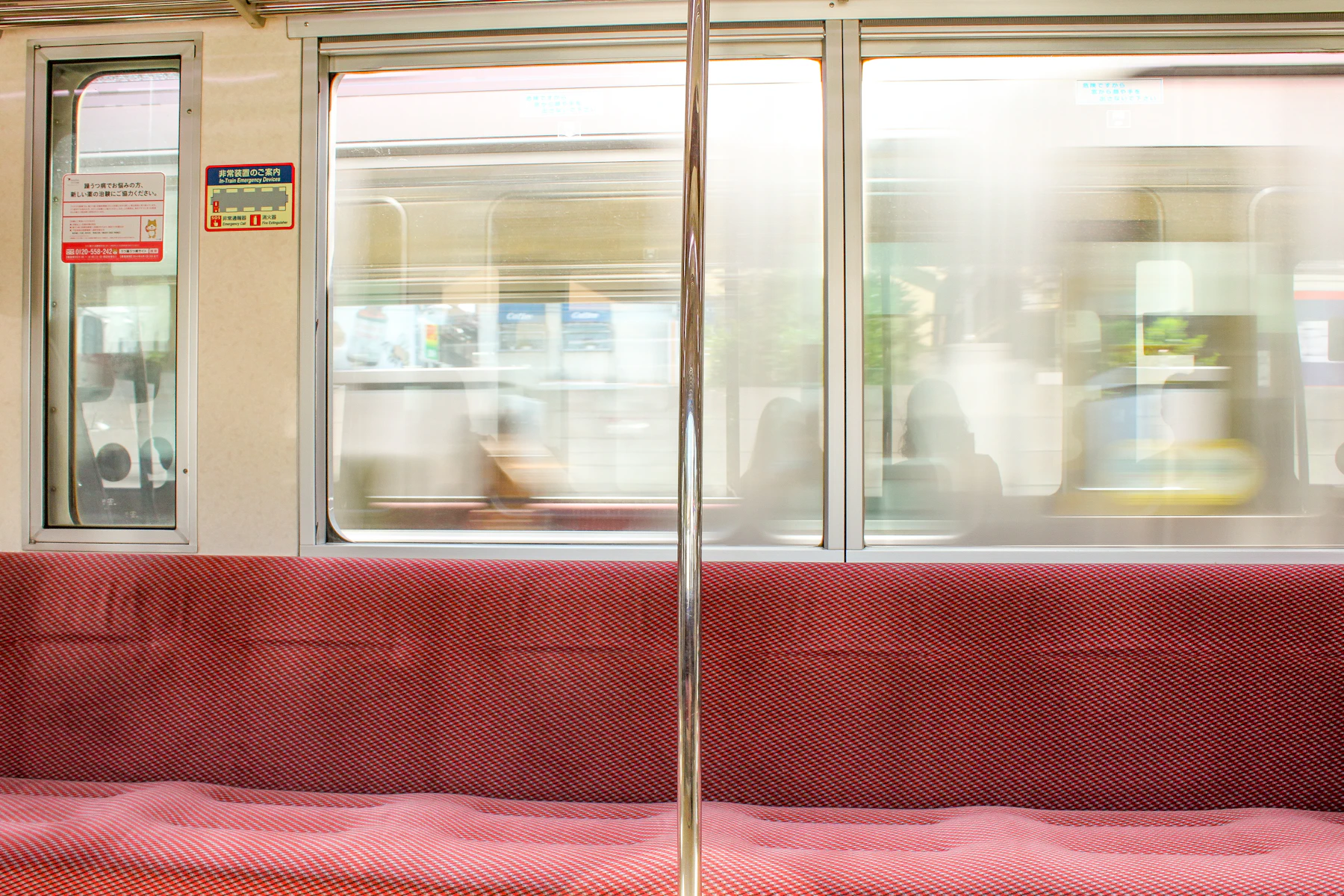 Un siège rouge confortable à côté d’une fenêtre de train, lumière douce de fin d’après-midi