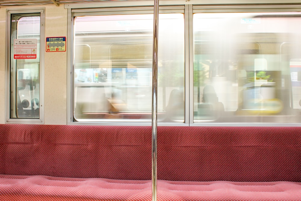 a red bench sitting next to a window on a train
