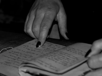 Close-up of a hand pointing at Indonesian phrases in a travel notebook.