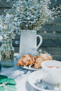An inviting breakfast nook set with pastel-colored mugs, a vase of fresh wildflowers, and a plate of homemade pastries.