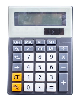 A simple electronic calculator with a large digital display at the top, featuring various mathematical function buttons such as addition, subtraction, multiplication, division, along with memory keys and special function keys. The numeric keypad is prominently displayed with numbers zero through nine.