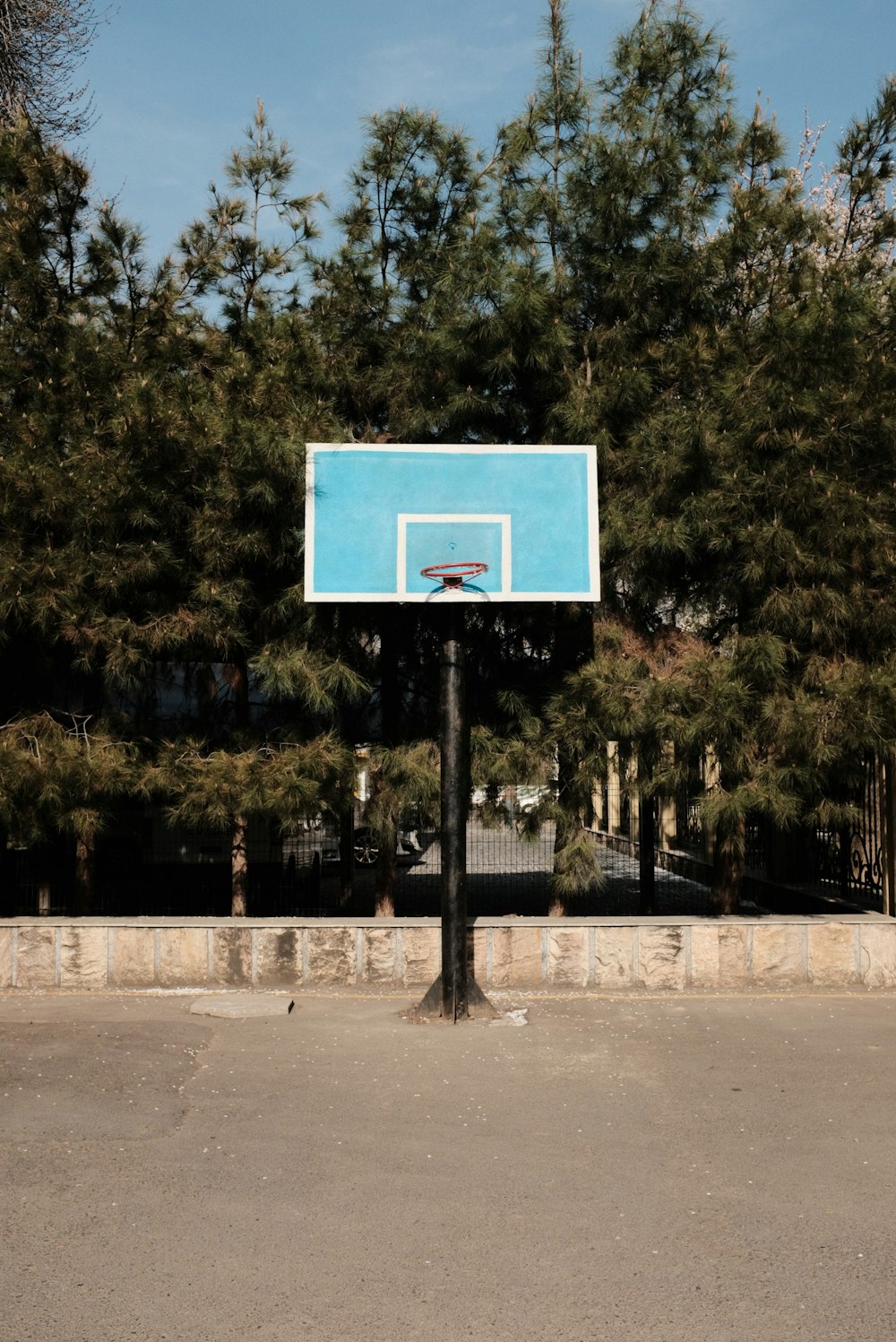 a basketball court with a blue backboard in front of some trees