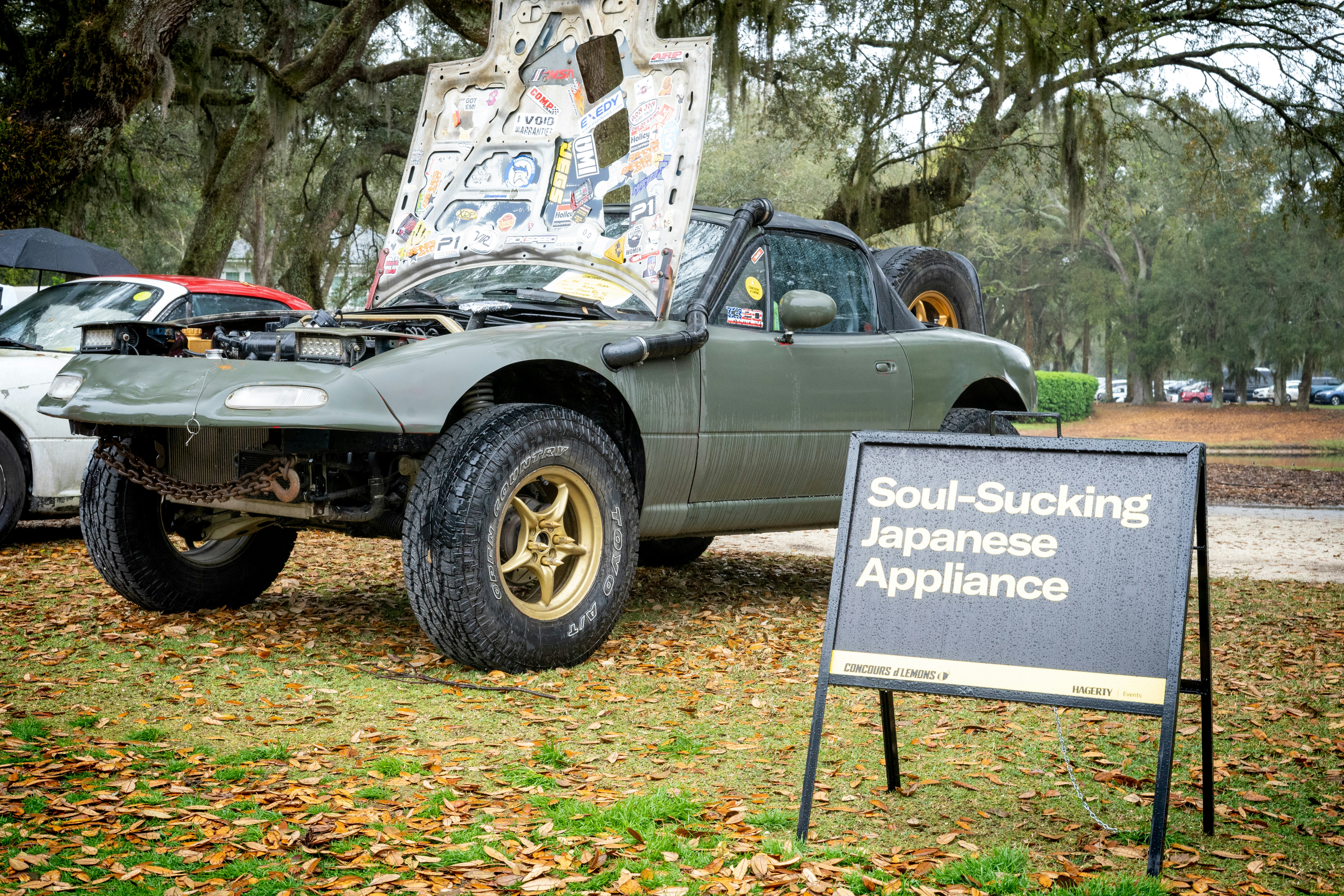 a truck parked in the grass with a sign in front of it, 