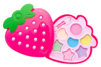 A pink, strawberry-shaped makeup kit with a green leafy top, featuring compartments with pastel-colored eyeshadows and shapes like stars and circles. The design is playful and colorful, aimed at children.