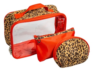 A set of three bags with leopard print designs and vibrant orange accents. The largest bag has a transparent front, a leopard print frame, and an orange handle, while the two smaller bags feature matching designs with orange zippers.