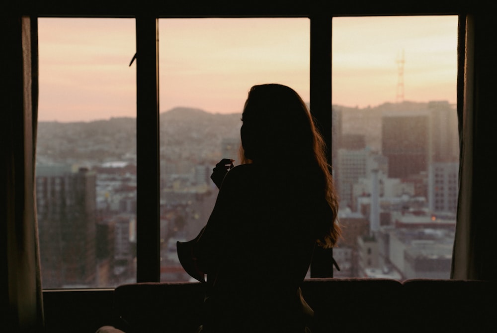 a woman looking out a window at the city