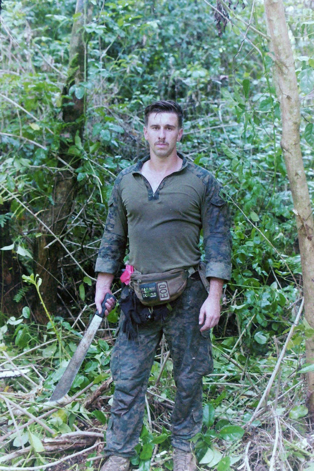 a man standing in the woods holding a knife