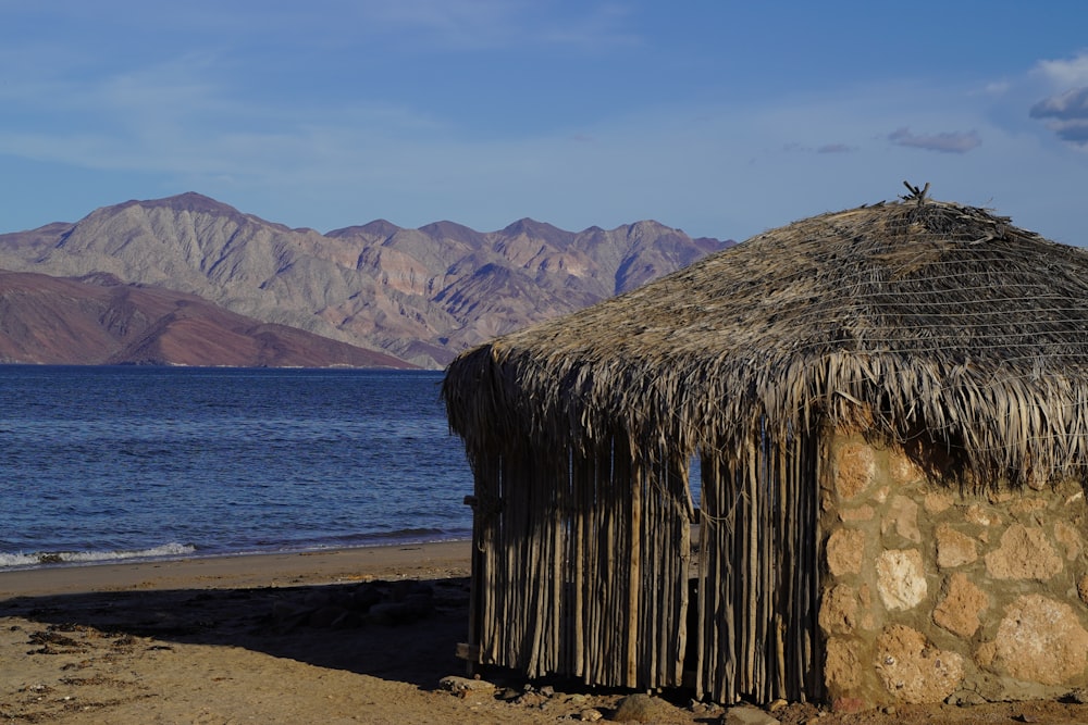 a hut on the beach with mountains in the background