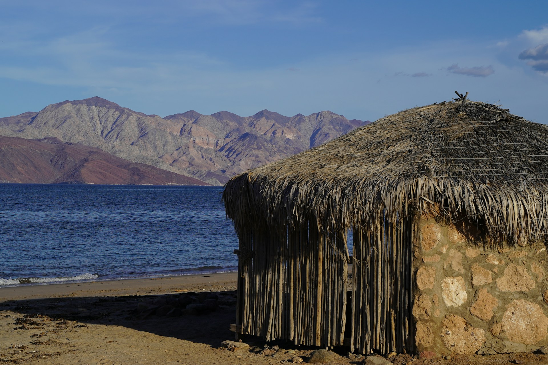 a hut on the beach with mountains in the background
