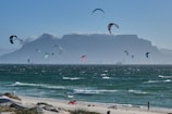 A panoramic view of a popular kitesurfing spot with mountains in the distance.