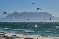 A panoramic view of the flat-water lagoon with colorful kites dotting the sky and surfers gliding across the water.