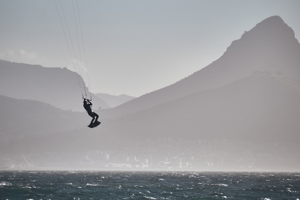 a person is parasailing in the ocean with mountains in the background