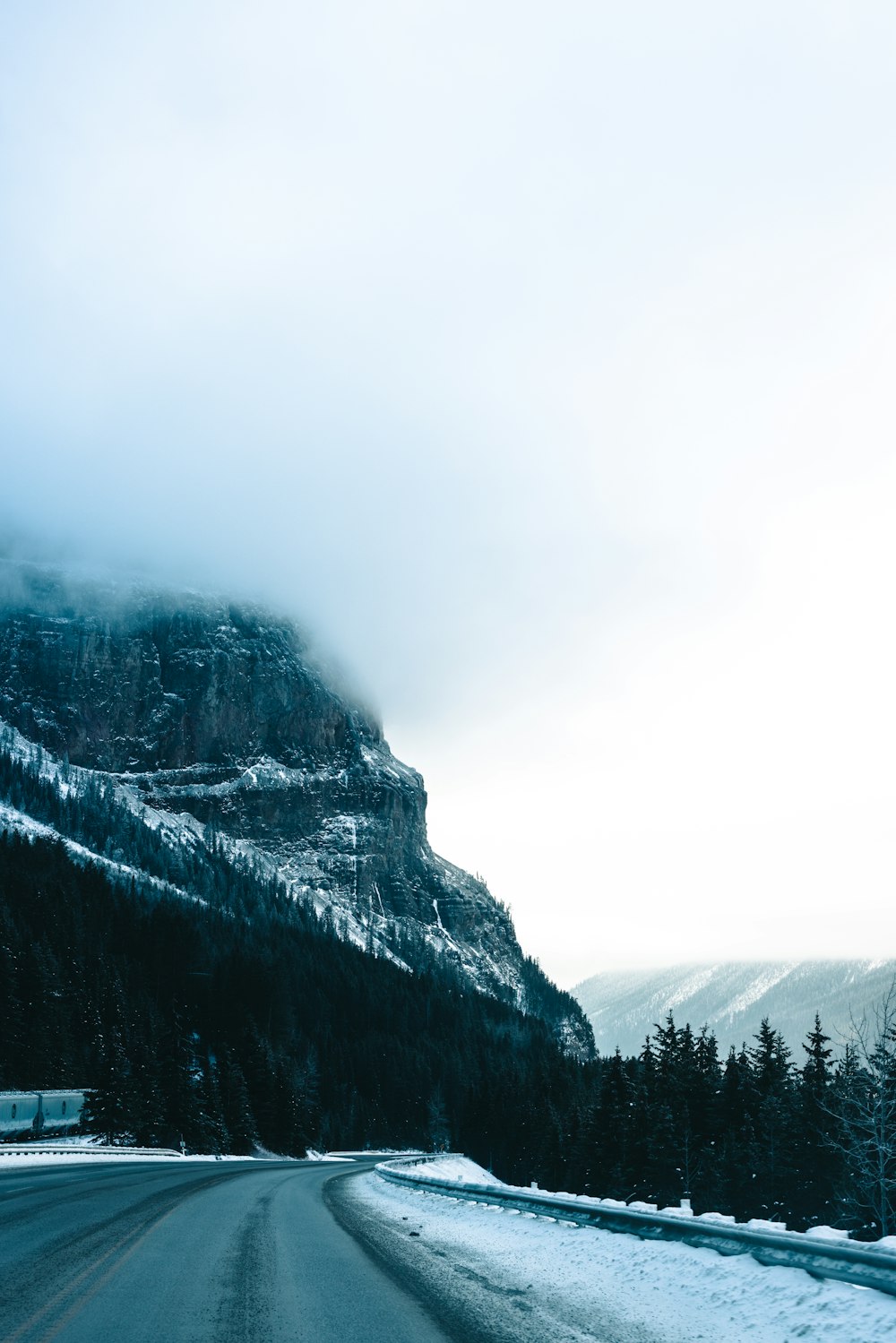 a snowy road with a mountain in the background