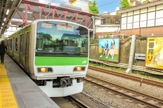 a green and white train pulling into a train station