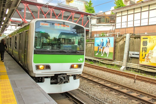 a green and white train pulling into a train station