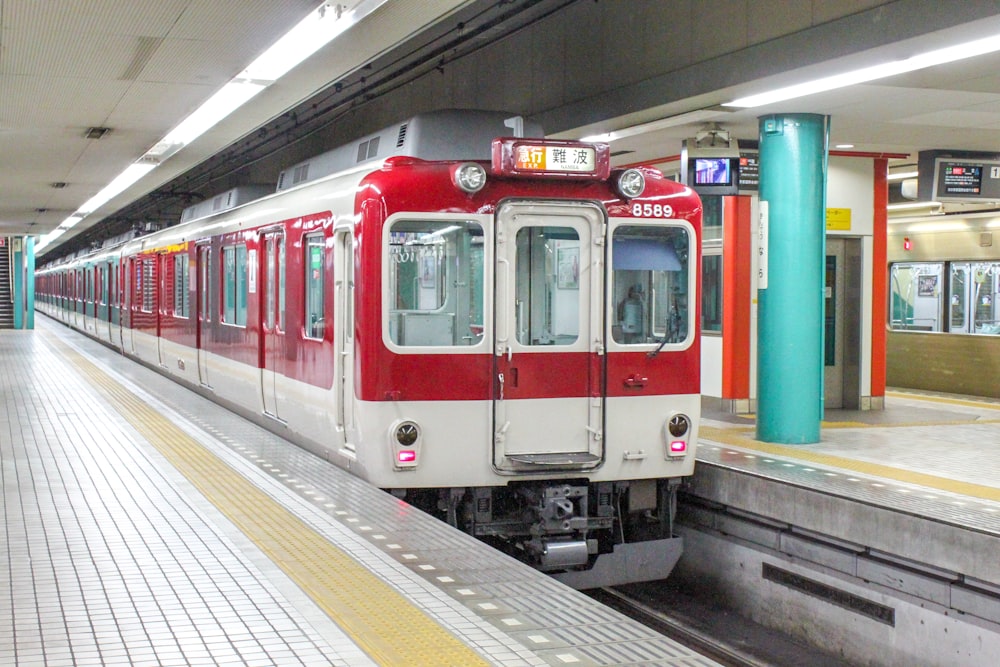 um trem vermelho e branco puxando para uma estação de trem