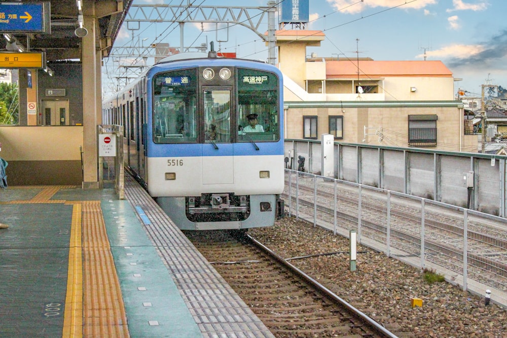 a blue and white train pulling into a train station