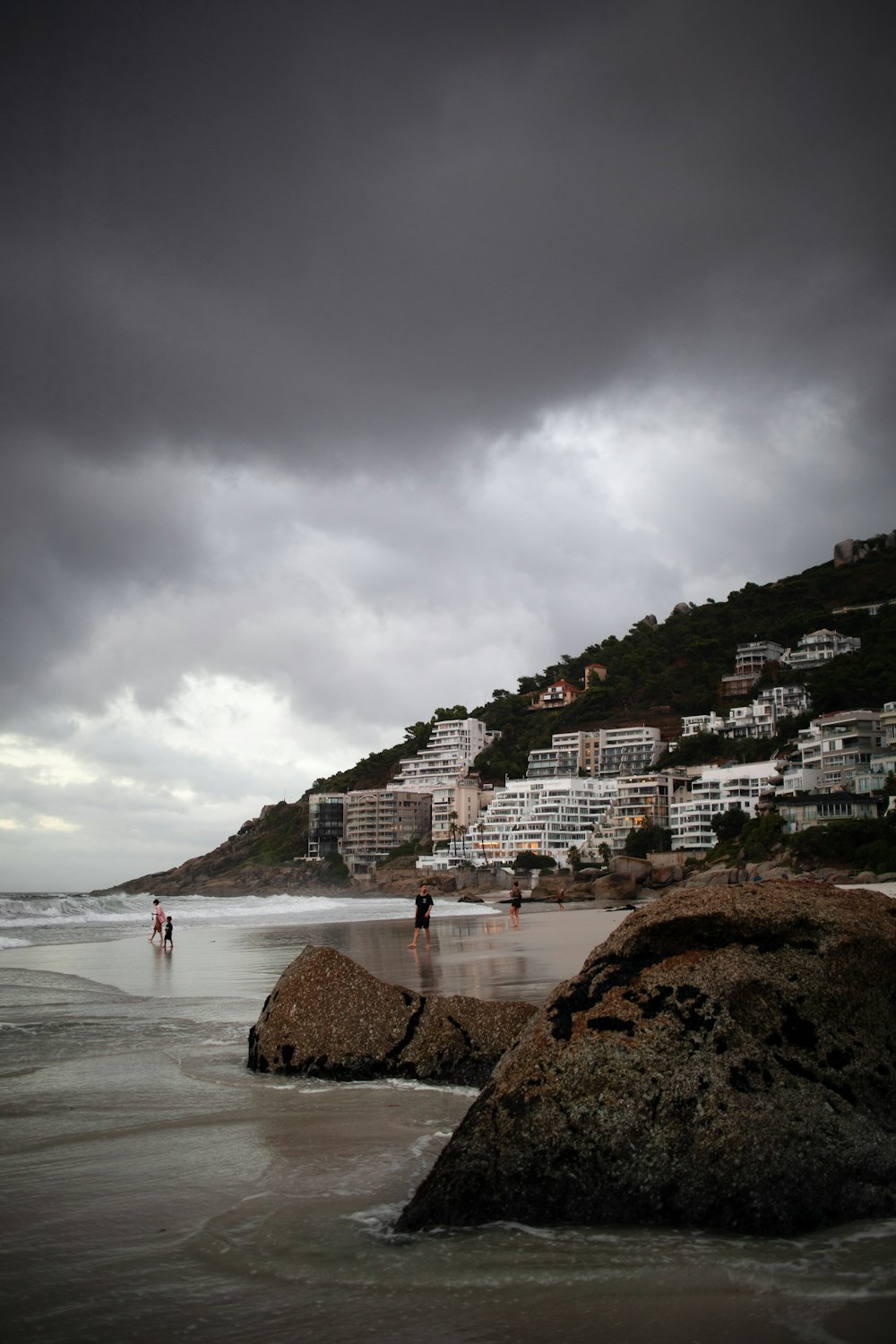 a couple of people standing on top of a sandy beach